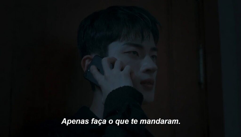 Seo Yi Do ao telefone ouvindo 'apenas faça o que te mandaram' em ambiente escuro