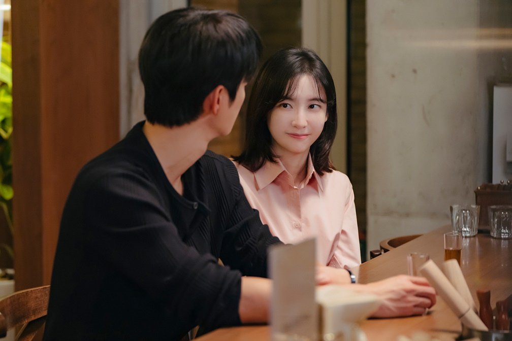 Park Ji-hyun como Cha Ji-yoon sorri olhando para Seo In-guk como Kang Si-woo em bar em Te vejo no trabalho