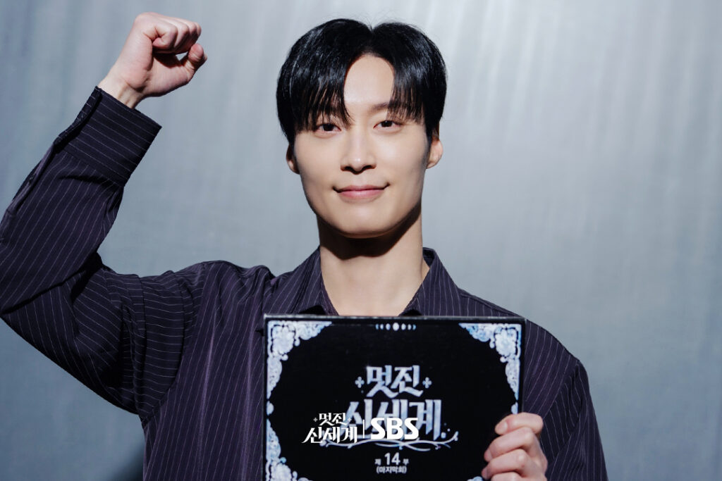 Heo Nam-jun sorri com o punho erguido segurando o roteiro do episódio final de My Royal Nemesis