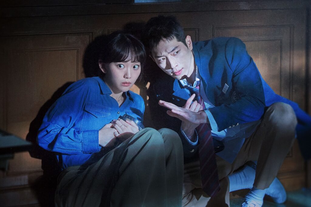 Seo Kang-jun como Jeong Hae-seong e Jin Ki-joo como Oh Soo-ah escondidos no escuro em cena de Infiltrado no Colégio