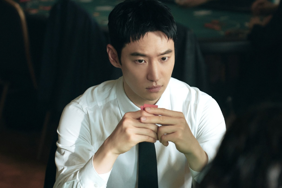  Lee Je-hoon como Kim Do-gi concentrado em mesa de jogo segurando ficha de cassino em O Taxista