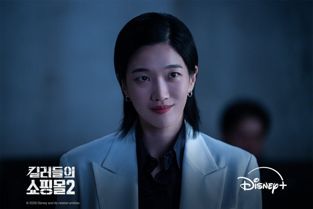Jung Yun-ha como Kusunagi de terno branco com sorriso enigmático em Uma Loja Para Assassinos 2