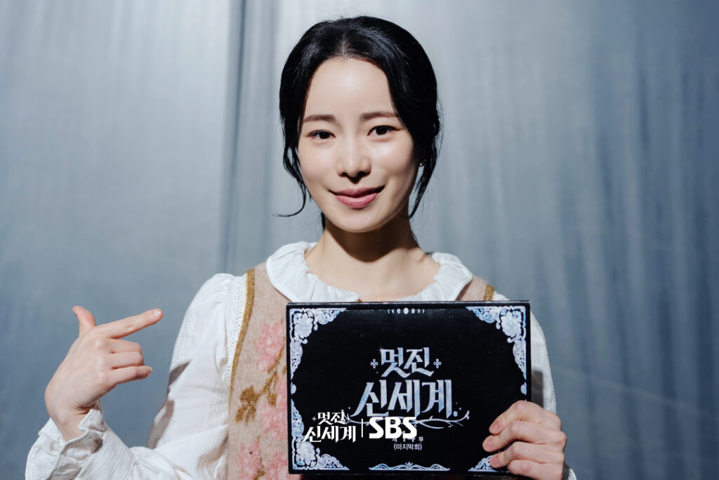Lim Ji-yeon sorri e aponta para o roteiro do episódio final de My Royal Nemesis em foto de despedida