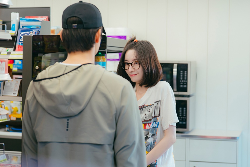 Seo In-guk de costas e Park Ji-hyun sorrindo timidamente se encontram na loja de conveniência em Te vejo no trabalho!