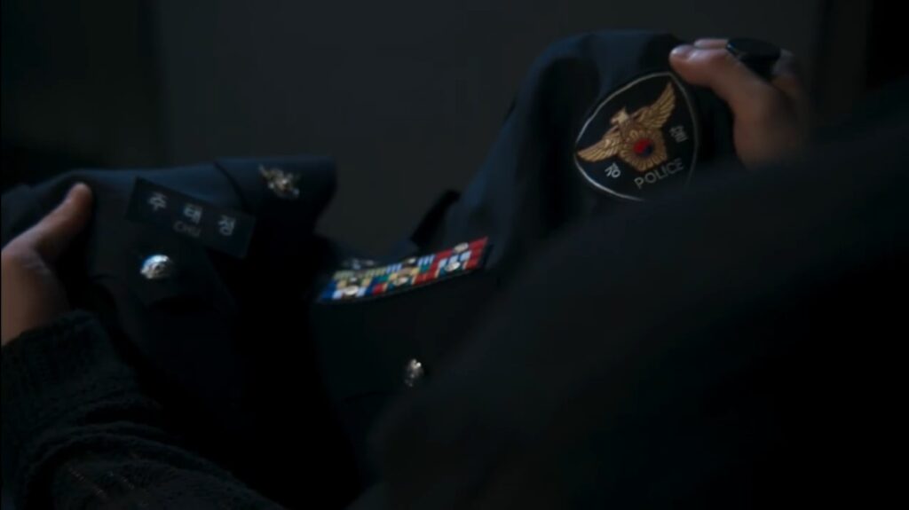 Uniforme policial de Chu Tae Jeong com crachá e insígnias à mostra