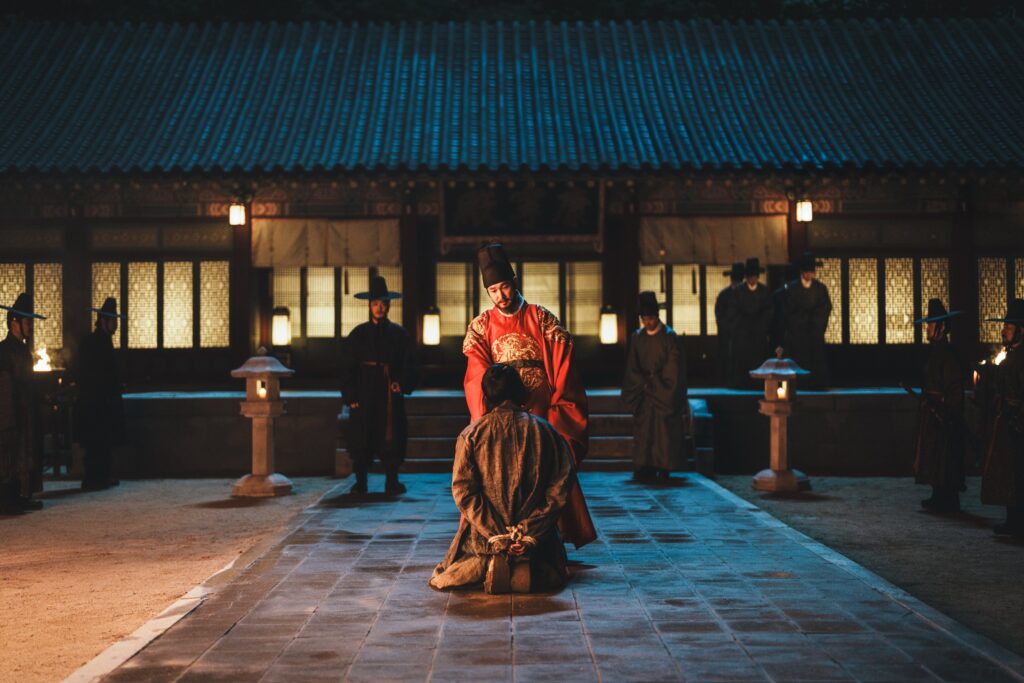 Cho Seung-woo como o Rei força Nam Joo-hyuk como Gu-cheon a se ajoelhar em cena de A Leste do Palácio