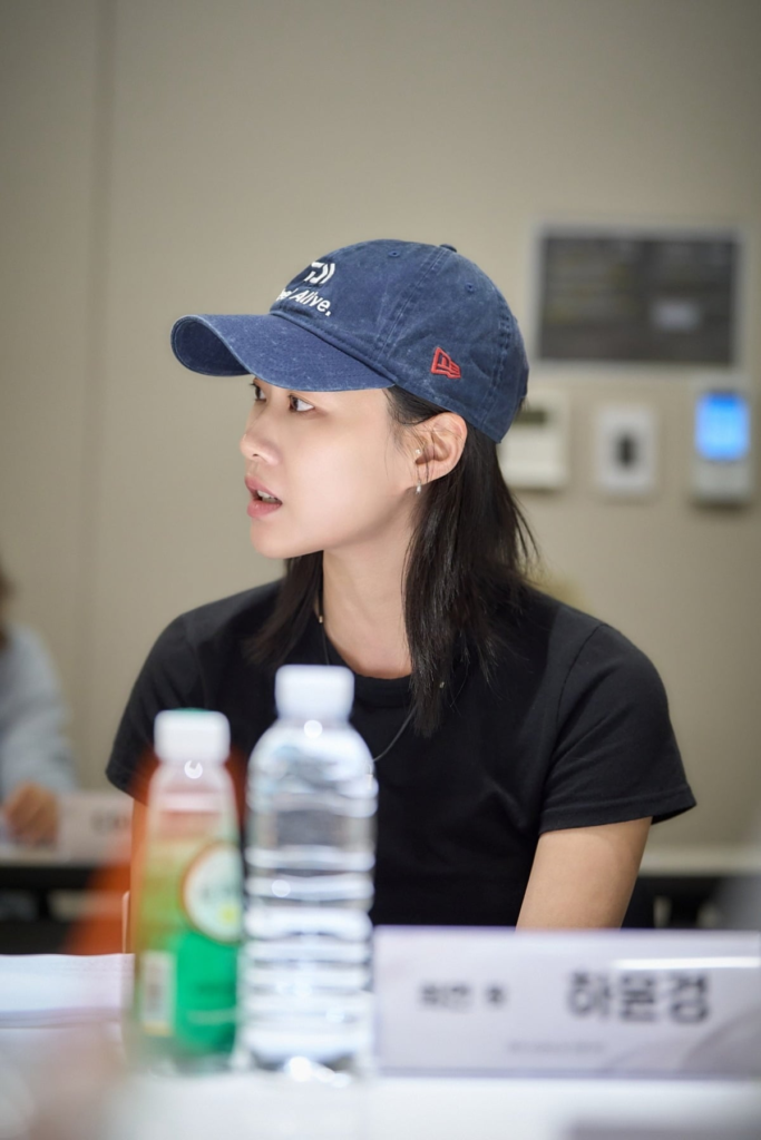Ha Yun-kyung de boné fala durante a leitura de roteiro de Dia Sem Maus Espíritos