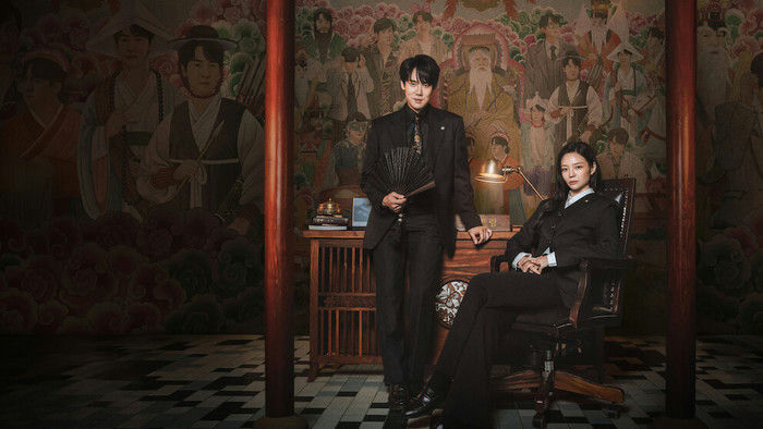 Lim Ji-yeon em traje histórico escuro ao lado de Heo Nam-jun em ambiente de trono em My Royal Nemesis