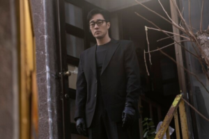 So Ji-sub em terno preto e luvas pretas em beco escuro em cena de ação de Agente Kim: Reativado