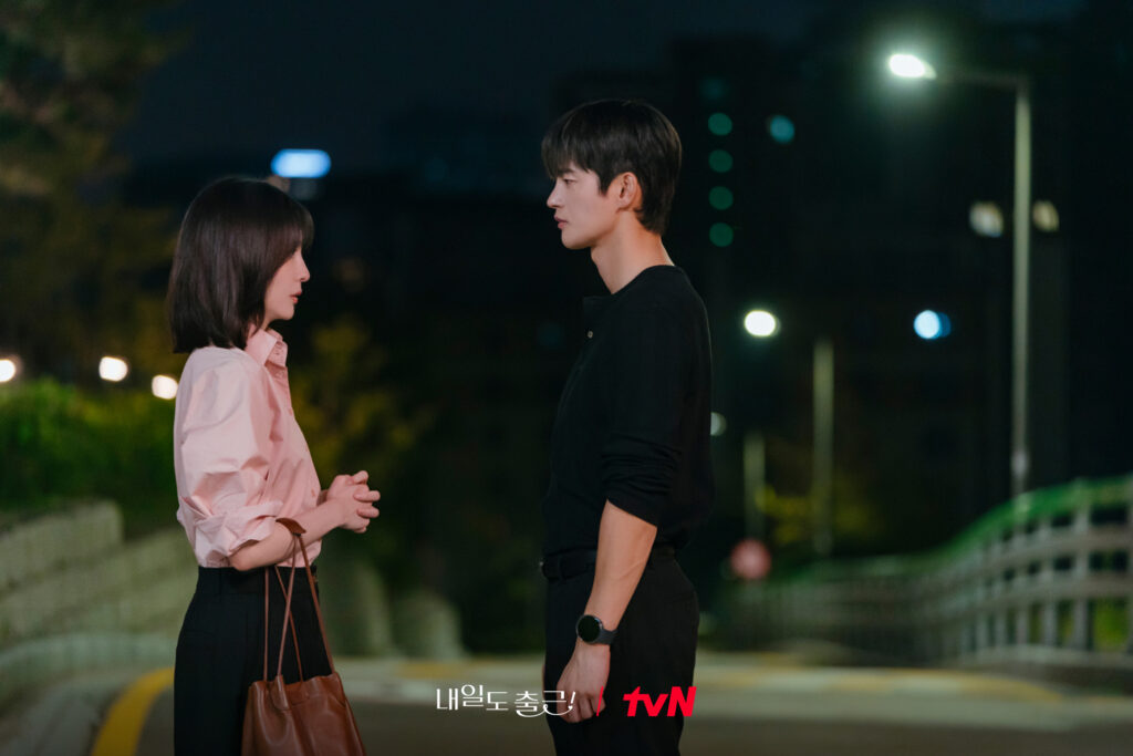 Park Ji-hyun como Cha Ji-yoon observa Seo In-guk com expressão atenta em rua à noite em Te vejo no trabalho