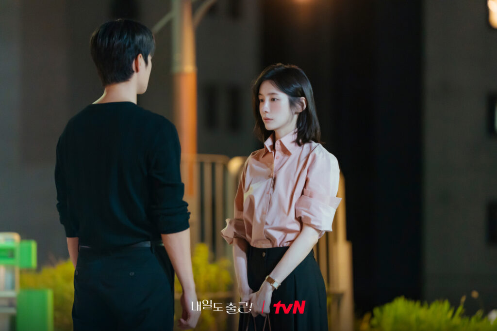 Seo In-guk e Park Ji-hyun de frente um para o outro em rua à noite em cena de Te vejo no trabalho