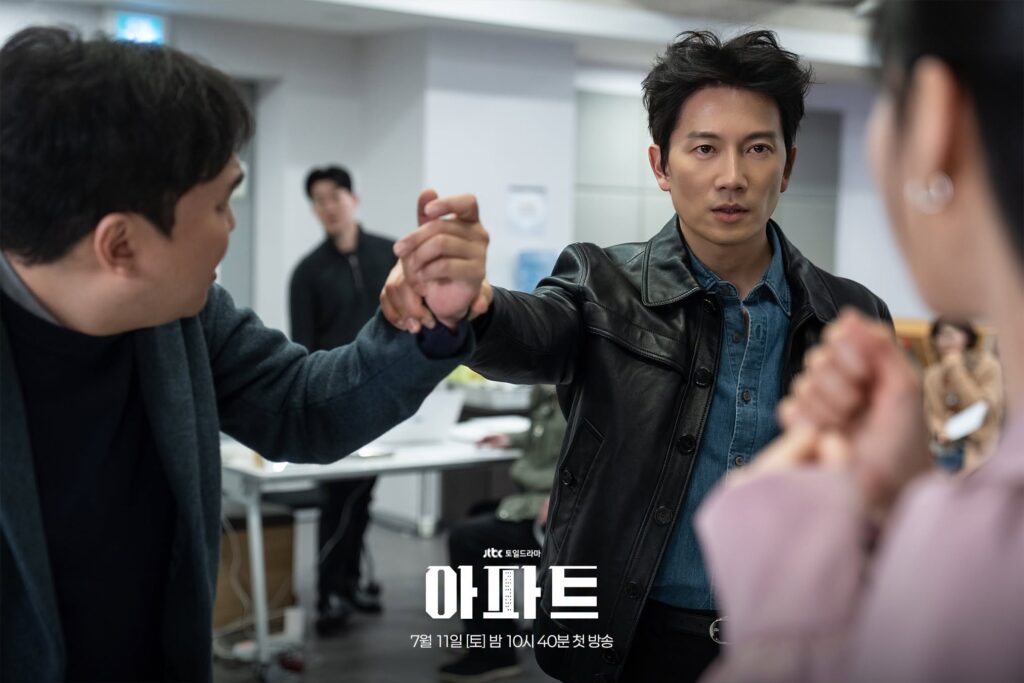 Ji Sung como Park Hae Kang segura o pulso de um cliente agressivo para proteger Ha Yun Kyung em cena de The Apartment Job
