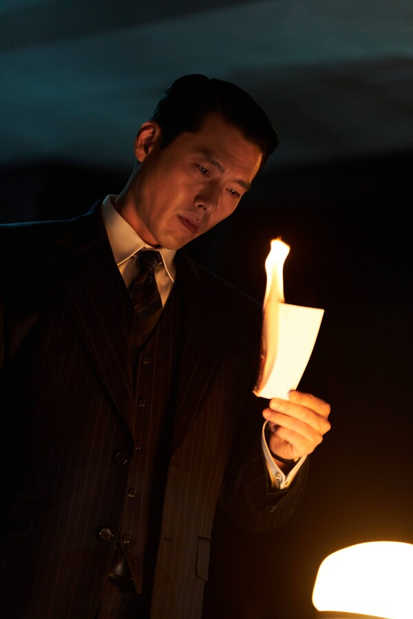 Hyun Bin como Baek Kitae observa papel queimando em Made in Korea 2
